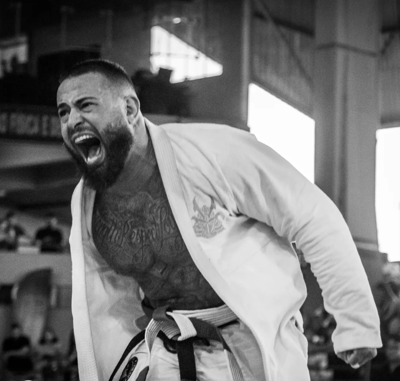 Uriel Meneses comemorando uma vitória de kimono branco e faixa preta, em foto preto e branco